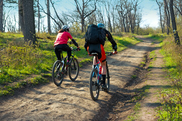 Couple cycling on the dirt road in the woods