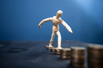 Stacks of golden coins like income graph and wooden man walking.