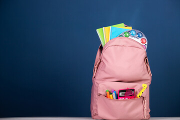 Backpack with different colorful stationery on table. Back to school