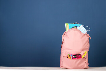  Backpack with different school stationery and medical mask. Coronavirus concept.