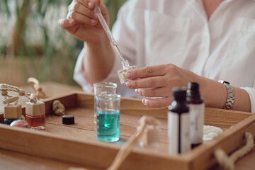 Close-up of a pipette with oil and a glass bottle. woman pouring perfume in bottle. Perfume creating workshop