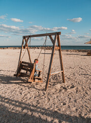 Little girl chilling resting in beach swing. Happy child smiling relaxing enjoying life sun fresh air. Lifestyle travel real people outdoor. Having fun vacation. Freedom happiness distance e-learning.