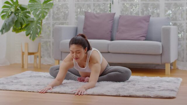 Happy Attractive Asian Pregnant woman practice yoga baddha konasana pose with meditation smile with big belly.Pregnancy woman do yoga butterfly so comfortable and relax,Healthcare Pregnant Concept