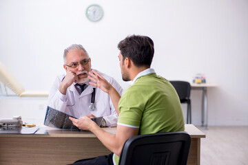 Young man visiting old male doctor radiologist