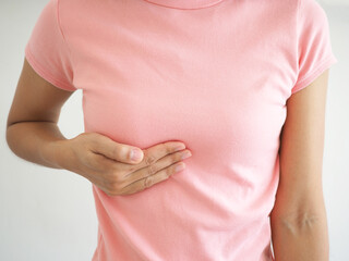 Young woman examining her breast for lumps or signs of breast cancer.