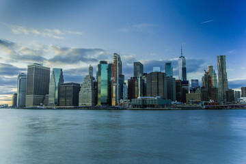 Naklejka premium Skyline di New York City. Fiume con palazzi illuminati come sfondo
