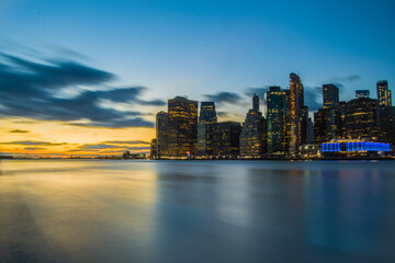 Skyline di New York City. Fiume con palazzi illuminati come sfondo. Foto Panoramica in lunga...