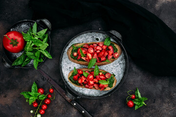 Bruschetta with pesto and tomatoes on a dark background