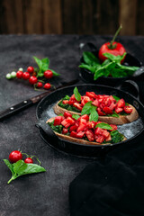 Bruschetta with pesto and tomatoes on a dark background