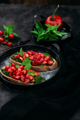 Bruschetta with pesto and tomatoes on a dark background