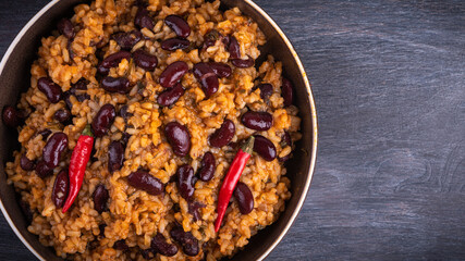 Mexican spicy tomato rice with beans and hot peppers on a plate, top view, copy space