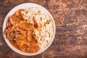 Hungarian chicken stew - chicken parikash with dumplings, gnocchi on plate, top view, copy space