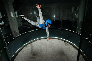 A young woman in overalls and a protective helmet enjoys flying in a wind tunnel. Free fall...