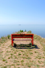 Red bench on the sea coast cliff