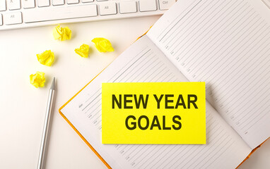 NEW YEAR GOALS text on sticker on the diary with keyboard and pencil