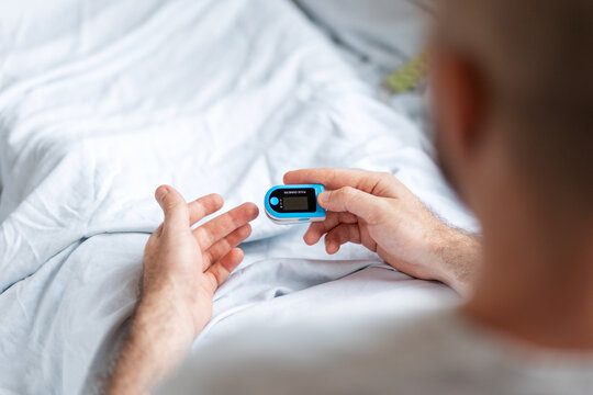 Patient lying at bed and wear a pulse oximeter. View from the shoulders. Concept of determination of oxygen in the blood