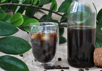 fresh iced black coffee in a glass with coffee beans and green  leaves