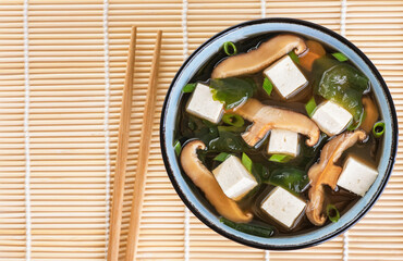 Japanese miso soup with shiitake mushrooms, tofu cheese, fresh onions and wakame seaweed. Top view.