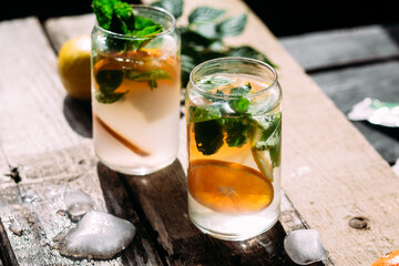 Cold cocktail with tangerine and mint on a wooden table