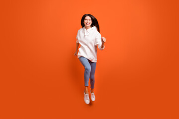 Full length body size view of attractive cheerful girl jumping running energy action isolated bright orange color background