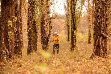 Obraz premium girl walks in the autumn forest. A young woman is spinning against the background of orange trees.