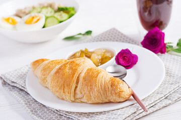 Breakfast oatmeal porridge with boiled egg, cucumber and croissant, jam, coffee. Healthy balanced food.
