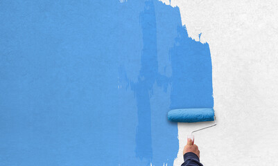 hand holds paint roller and painting a wall
