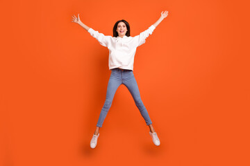 Fototapeta na wymiar Full length body size view of pretty carefree cheerful girl jumping having fun isolated over bright orange color background