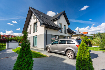 Driveway of a modern single-family house with a green garden at summer