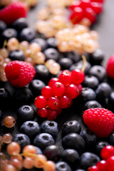 Fresh summer berries in vintage mug over black background, top view