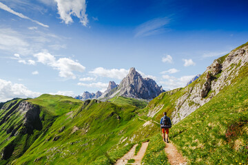 Young man with backpack on a mountain trail, Dolomites Mountains, Italy