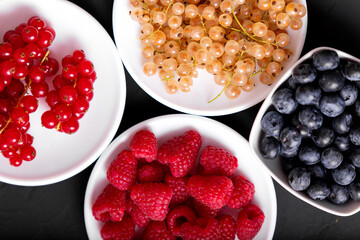 Fresh summer berries in vintage mug over black background, top view