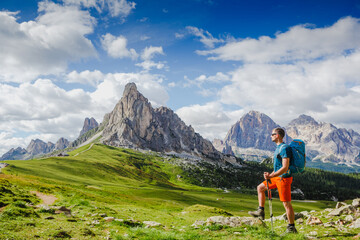 Fototapeta premium Young man with backpack on a mountain trail, Dolomites Mountains, Italy