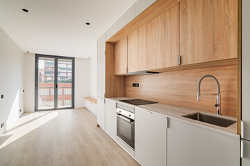 Contemporary minimal kitchen and living room with balcony at empty refurbished apartment. Wooden...