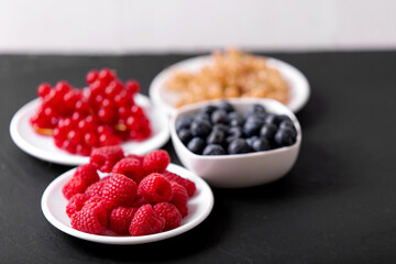 Fresh summer berries in vintage mug over black background, top view