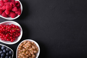 Fresh summer berries in vintage mug over black background, top view