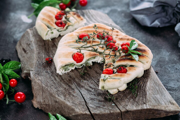 Focaccia with tomatoes and herbs on a wooden table