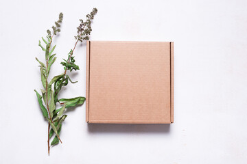 Brown cardboard mailer box decorated with dried leaves