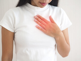 Young woman touching chest. Heart attack, heart disease, and chest pain concepts, on white...