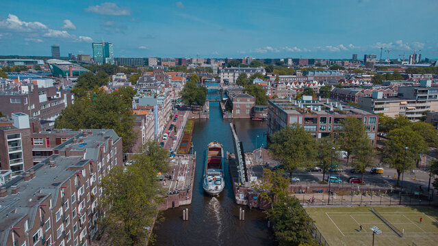 Aerial drone view of a ship passing elevating road bridge in amsterdam canal. Ship under open bridge over the canal.