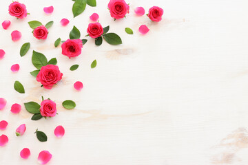 White wooden delicate background with pink roses and petals. Top view