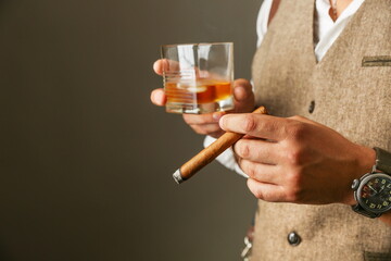man holds cigar and glass of whiskey close up. concept of cigar club