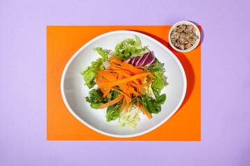 top view salad plate and cockles with orange and purple bicolor background with copy space