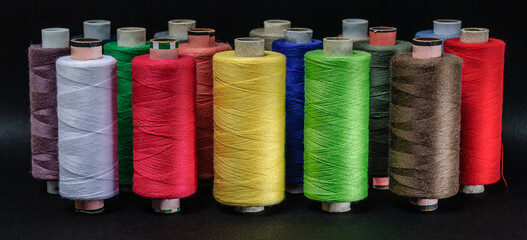 colorful spools of thread on black background