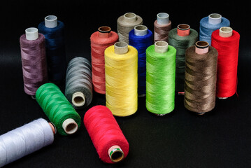 colorful spools of thread on black background