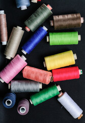 colorful spools of thread on black background
