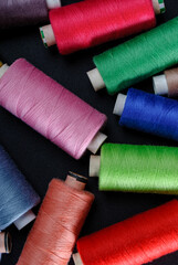 colorful spools of thread on black background
