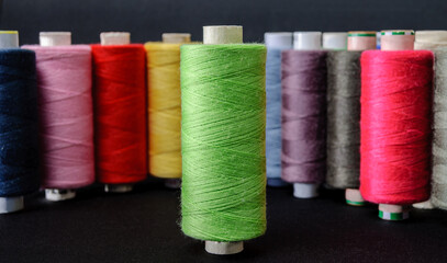 green spool in focus against colorful spools of thread background