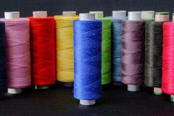 colorful spools of thread on black background