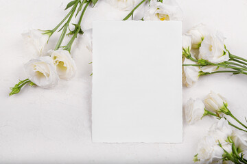 Obraz na płótnie Canvas Vertical empty 7x5 card mockup with blooming white eustoma lisianthus flowers, design element for wedding invitation, thank you or greeting card. Spring background